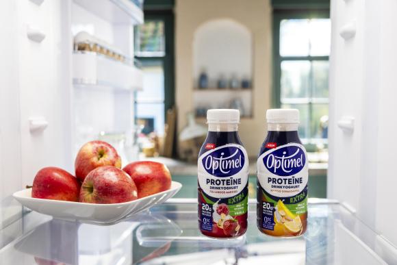 De 2 nieuwe smaken Optimel Proteïne Extra naast een schaal appels in de koelkast.