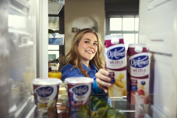 Vrouw pakt pak Optimel vezels drinkyoghurt uit koelkast